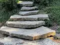 Kamienne stopnie prowadzą na taras przez zielony skalniak.