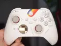 Biały kontroler Xbox z tęczowym paskiem i oznaczeniami przypominającymi kokpit. Idealny do testów xbox pad.