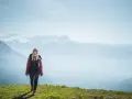 Frau in Wanderkleidung genießt die Aussicht auf verschneite Berge. Perfekt, was zieht man zum wandern an!
