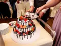 Piękne torty weselne z owocami, ozdobione czekoladą i świeżymi jagodami, malinami i truskawkami. Para kroi pierwszy kawałek.