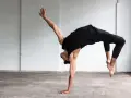 Un bailarín en un estudio blanco realiza un movimiento acrobático, mostrando que es la danza.