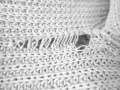 Nahaufnahme eines weißen Strickpullovers mit einem Loch und ausgefransten Fäden. Was tun, wenn die Wolle eingelaufen ist?
