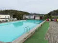 En stor pool med turkost vatten och solstolar i färgglada nyanser. En perfekt plats för avkoppling på camping Orust.