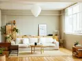 Salones nórdicos con sofá blanco, mesa de centro de madera y estanterías de pino. Luz natural entra por la ventana.
