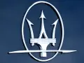 Błyszczący, chromowany trójząb Neptuna, czyli jak wygląda znaczek Maserati, na ciemnoniebieskim tle.