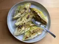 Ugnsbakad spetskål med citron och örter, serverad på en tallrik med en sked.