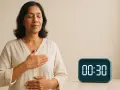 Donna con occhi chiusi e mani sul petto e addome, pratica la respirazione per ansia. Timer digitale segna 00:30.