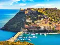 Incantevoli toscana paesaggi: un borgo colorato su una collina fortificata domina un porto con barche, baciato dal sole.