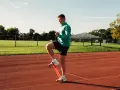 Uomo si allena con elastico sulle caviglie in pista, pronto a riprendere a correre.