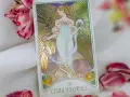 La carta de la templanza tarot, con su figura etérea vertiendo agua, rodeada de pétalos de tulipán rosa y blanco, evoca serenidad y equilibrio.