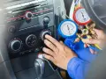 Mechanik sprawdza ile czynnika do klimatyzacji pozostało w samochodzie, używając manometrów.