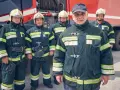 Strażacy w mundurach przy wozie strażackim. Zastanawiasz się, ile zarabia aspirant w straży pożarnej?