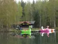 Bunte Tretboote in Form von Schwänen und Einhörnern liegen am Ufer des Bruchsee Duingen. Ein Gebäude mit der Aufschrift "FOOD" und Solaranlagen steht im Hintergrund.
