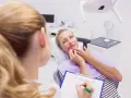 Kobieta w ciąży konsultuje z dentystką co na ból zęba w ciąży. Dentystka notuje na kartce.