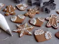Pepparkakshus och hjärtan dekorerade med vit kristyr. En sprits med kristyr ligger bredvid.