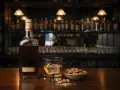 Butelka amaretto, szklanka z lodem i skórką pomarańczy, miseczka migdałów. Idealne połączenie, by dowiedzieć się, amaretto co to.