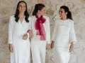 Tres mujeres sonríen vestidas de blanco, demostrando que se puede ir de blanco a un bautizo.
