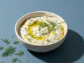 Schüssel mit cremigem Tzatziki, garniert mit Olivenöl und Dill. Perfekt für Ihr nächstes Tzatziki Rezept.