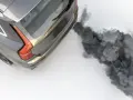 Ein graues Auto stößt beim Gas geben schwarzen Rauch aus dem Auspuff.
