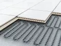 Coupe d'un sol carrelé montrant le système de chauffage au sol : câbles chauffants sous une couche isolante et un support, puis les carreaux.