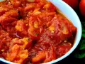 Un tazón de tomates picados, jugosos y vibrantes, con un toque de albahaca fresca y dos tomates enteros al fondo. Un bonito con tomate listo para disfrutar.