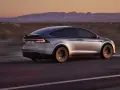 Srebrny Tesla X pędzi przez pustynny krajobraz o zachodzie słońca. Zastanawiasz się nad jego ceną?