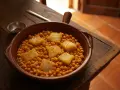Guiso de garbanzos con trozos de bacalao en cazuela de barro.