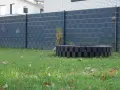 Moderner Sichtschutzzaun, der sich gut zum zaun selber bauen billig eignet. Ein dekorativer Kreis aus schwarzen Steinen im Garten.