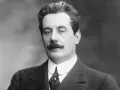Giacomo Puccini, kompozytor słynnych **puccini opery**, w eleganckim garniturze i z charakterystycznymi wąsami.