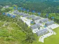 Widok z lotu ptaka na osiedle budynków mieszkalnych otoczone lasem, z oznaczeniami budynków.