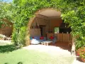 Un jardín con una madreselva planta cubriendo un arco de piedra. Dentro, sofás y una barra de madera.