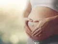 Czekając na dziecko, zastanawiasz się, czy autyzm można wykryć w ciąży? Dłonie tworzą serce na brzuchu.