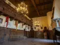 Wnętrze zamku Czocha z bogatymi zdobieniami, portretem króla i banerami. Bilety do zamku czekają na odkrycie jego historii.