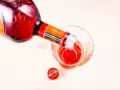Czerwony Martini Fiero drink nalewany z butelki do szklanki. Obok leży czerwona zakrętka z logo Martini.