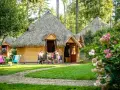 Famille profitant d'un repas en terrasse devant leur chalet en chaume, parfait pour des vacances scolaires en Bretagne.