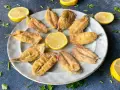 Deliciosos boquerones al limón, crujientes y dorados, servidos en un plato con rodajas de limón y perejil fresco.