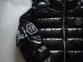 Błyszcząca, czarna kurtka Philipp Plein z futrzanym kapturem i białym logo na rękawie.