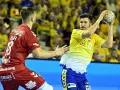 Piłkarz Aalborg Handball w żółtej koszulce rzuca piłkę, obok zawodnik w czerwonej.