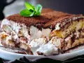 Tiramisú cremoso cubierto de cacao y decorado con menta.
