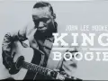 John Lee Hooker, King of the Boogie, spielt Gitarre. Sein Blick ist konzentriert, während seine Finger über die Saiten gleiten.