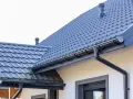 Szary dach z dachówki ceramicznej, idealny do obliczenia dachówka ceramiczna cena za m2. System rynnowy odprowadza wodę.