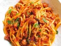 Linguine al ragù di pesce, un piatto saporito con polpo e pomodoro, guarnito con prezzemolo fresco.