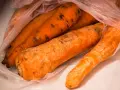 Kilka pomarańczowych marchewek w plastikowej torbie, na których widać ciemne plamy, oznaki pleśni.