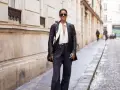 Mujer con gafas de sol y chaqueta de cuero, luciendo un elegante pantalón flare que es tendencia.