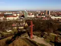 Góra Gradowa z czerwonym monumentem w kształcie krzyża na tle panoramy miasta.