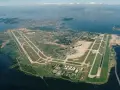 Lotnisko Rio de Janeiro z lotu ptaka, z pasami startowymi i terminalem, otoczone wodą i zielenią.