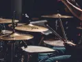 Perkusista w akcji, pałeczki unoszą się nad werblem, tworząc rytmiczne **modal scales** w mroku sceny.