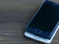 Dwa smartfony leżą na drewnianym blacie. Jeden, ciemny, spoczywa na drugim, srebrnym. Chciałbym skopiować moje urządzenie.
