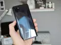Dłoń trzyma błyszczący, czarny telefon Samsung A81 z modułem aparatów.