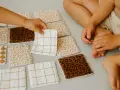 Petites mains d'enfant choisissant parmi des lingettes lavables bébé aux motifs variés : léopard, carreaux, et quadrillés. Idéal pour le change.